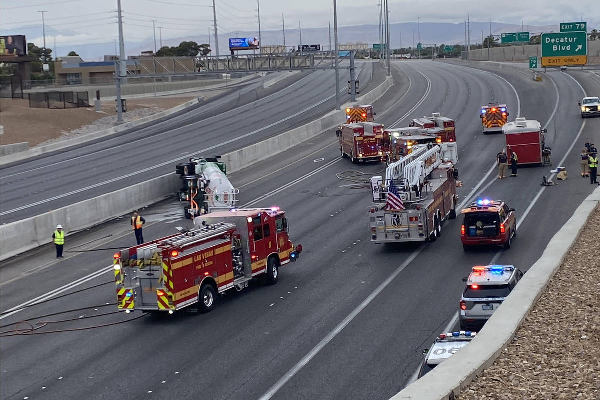 Emergency personnel work at the scene where a fuel tanker truck overturned on U.S. Highway 95 o ...