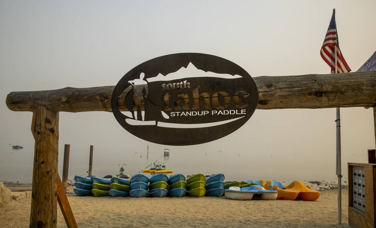 Paddle boards and boats are idle as smoke fills the sky over the lake from the nearby Caldor Fi ...