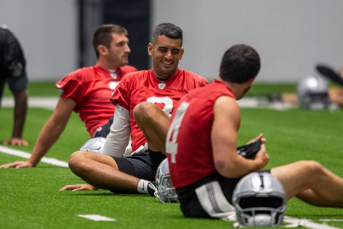 Raiders quarterback Marcus Mariota (8) and Raiders quarterback Derek Carr (4) share a laugh dur ...