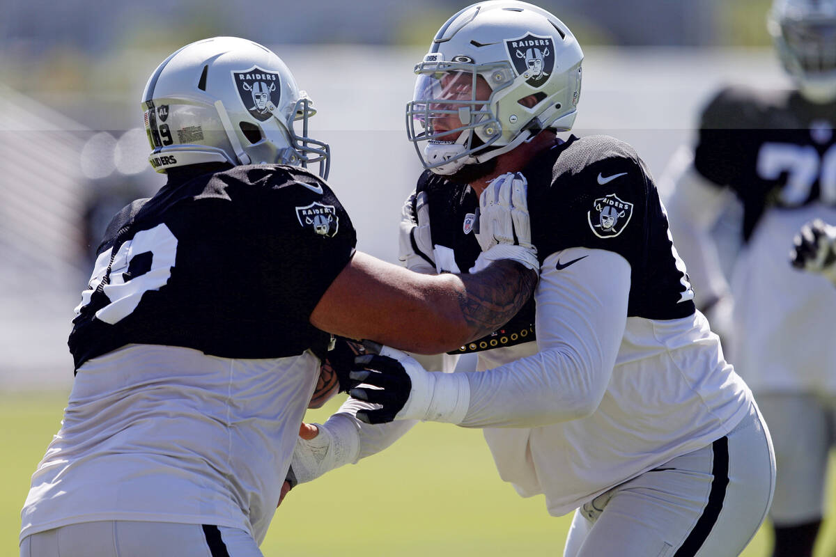 Raiders offensive lineman Jeremiah Poutasi (79) pushes center Andre James (68) during a drill a ...