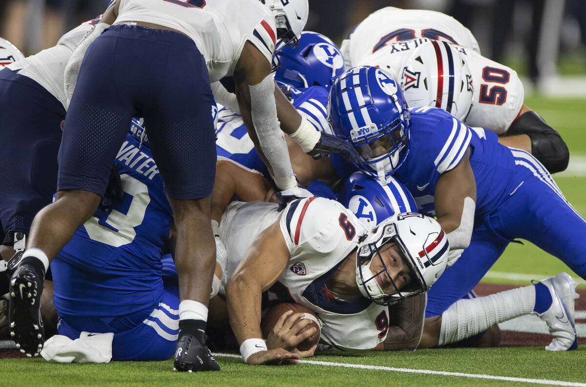 Arizona Wildcats quarterback Gunner Cruz (9) is tackled by Brigham Young Cougars defensive back ...