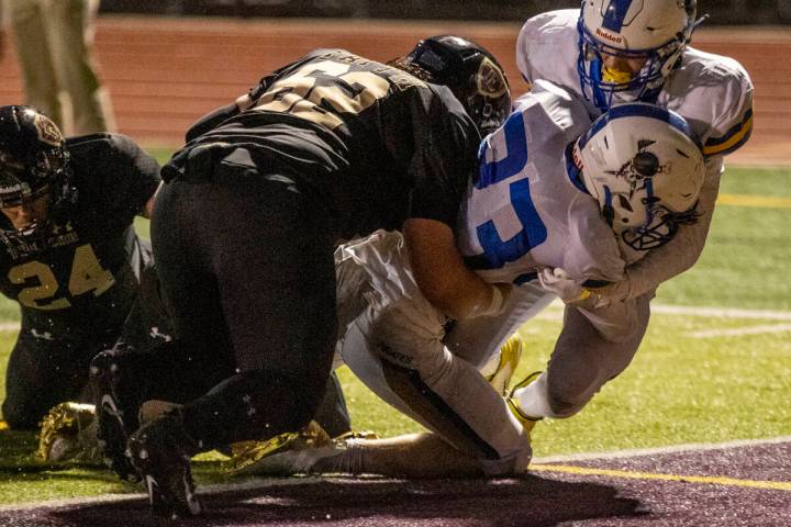 Moapa Valley's Landon Wrzesinski (23) scores with Faith Lutheran's Beau Graham (62) on his back ...