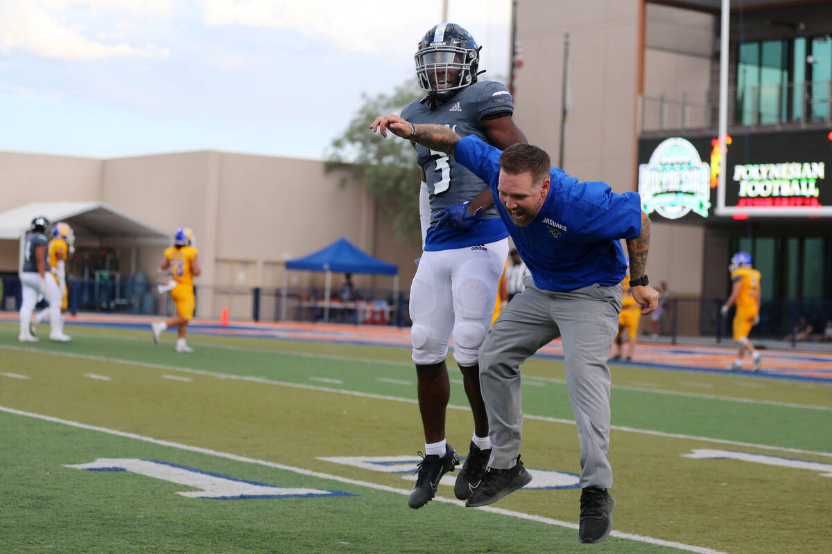 Desert Pines' Izley Manutai (13) celebrates a touchdown with a member of the coaching staff in ...