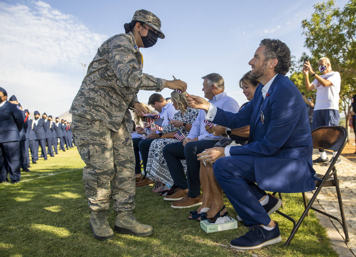 Air Force JROTC cadet Nicole Macario, left, hands small American flags to Brad Edwards and fami ...