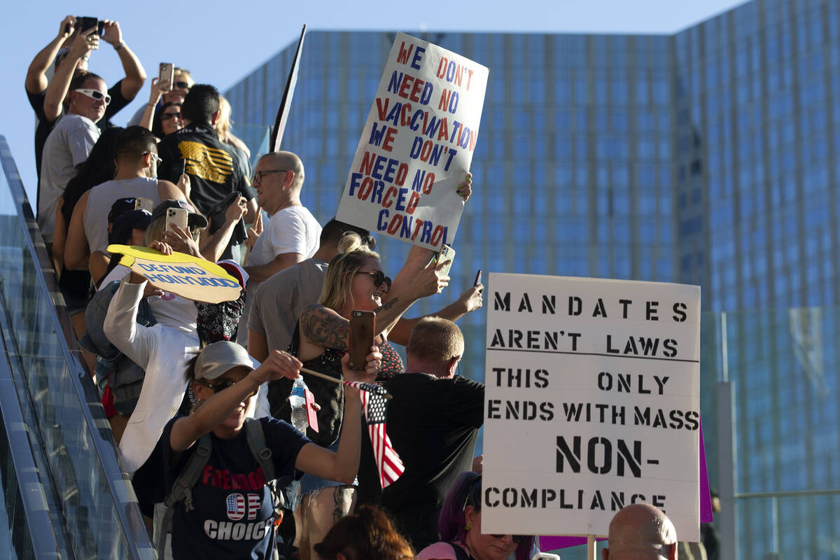 Demonstrators ride an escalator outside Planet Hollywood during an anti-mask, anti-vaccination ...