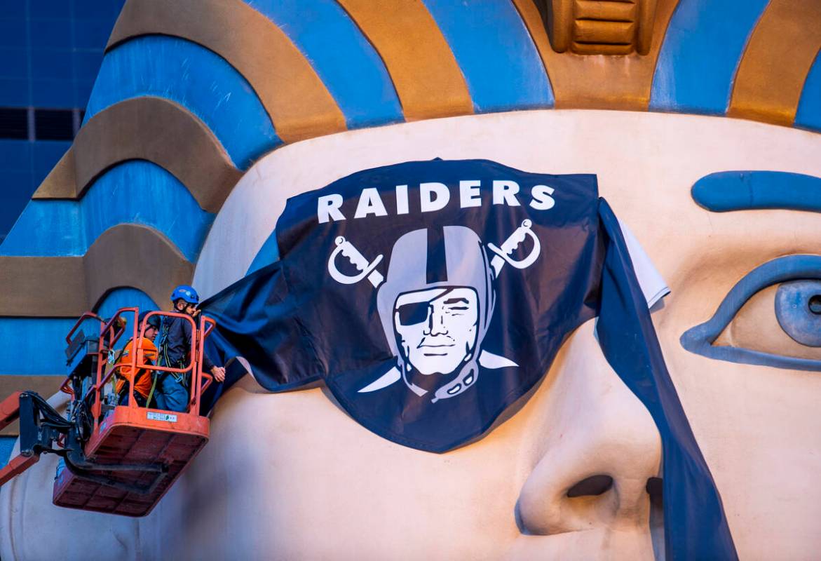 Billy Baker, left, and Miguel Lopez with Access Solutions hang a Raiders eye patch on the Great ...