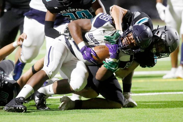 Shadow Ridge High School's Jaquieze Holland (25) is tackled by Silverado High School's Jaden Th ...