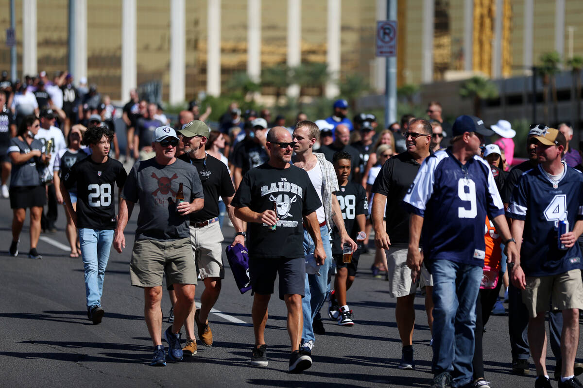 Fans cross the Hacienda Avenue bridge toward Allegiant Stadium for a game between the Raiders a ...