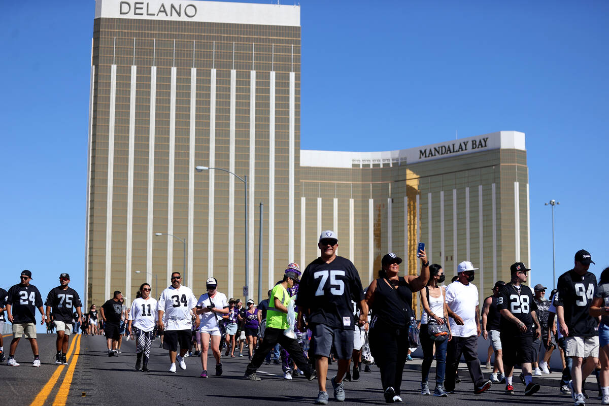 Fans cross the Hacienda Avenue bridge toward Allegiant Stadium for a game between the Raiders a ...