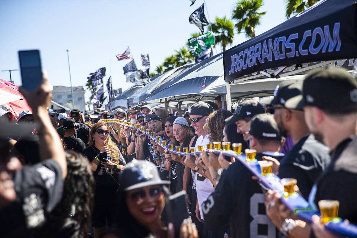 Over 100 football fans prepare to take shots while tailgating before an NFL game between the Ra ...