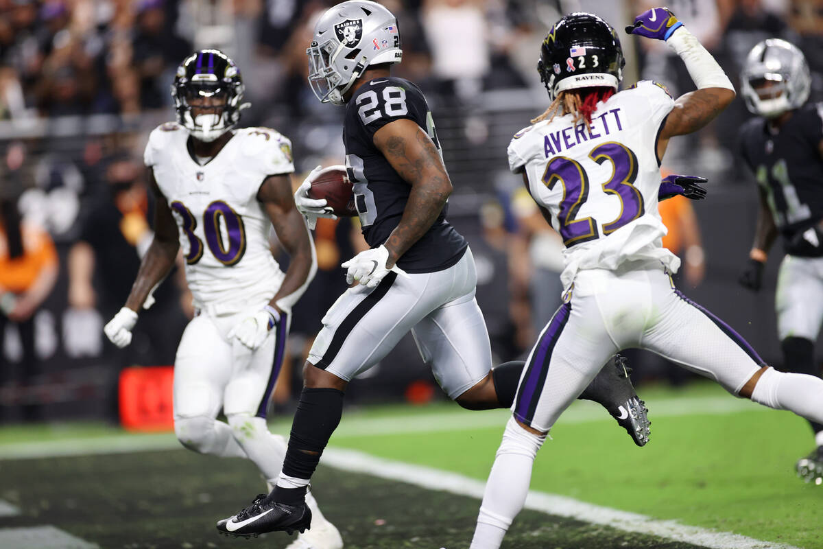 Raiders running back Josh Jacobs (28) runs for a touchdown under pressure from Baltimore Ravens ...