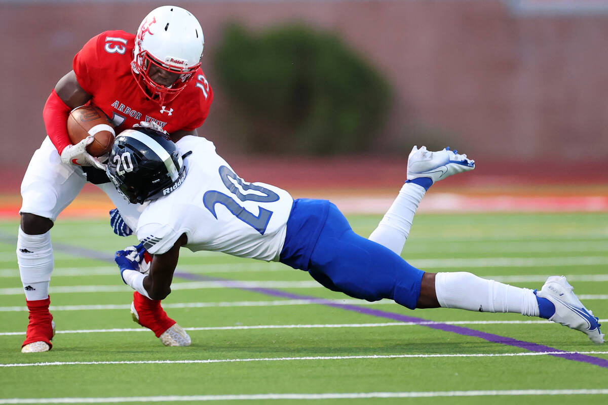 Arbor View's D'Andre Washington (13) is tackled by Desert Pines Isaiah Rubin (20) in the first ...