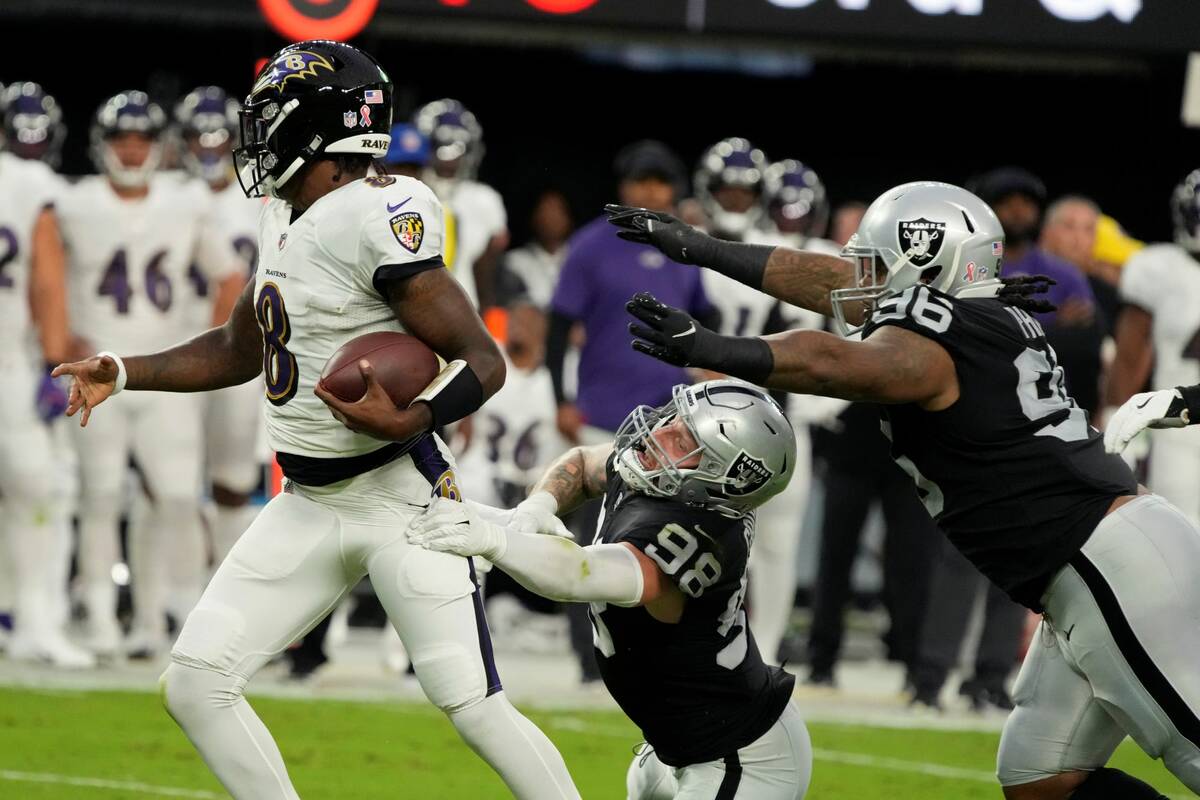 Las Vegas Raiders defensive end Maxx Crosby (98) grabs Baltimore Ravens quarterback Lamar Jacks ...