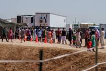 Afghan refugees line up for food outside a dining hall at Fort Bliss' Doña Ana Village whe ...