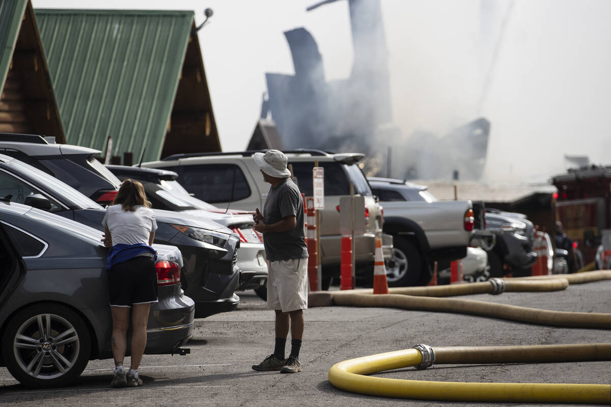 Residents, including Anthony Armas, right, watch as firefighters battle a blaze at Mount Charle ...