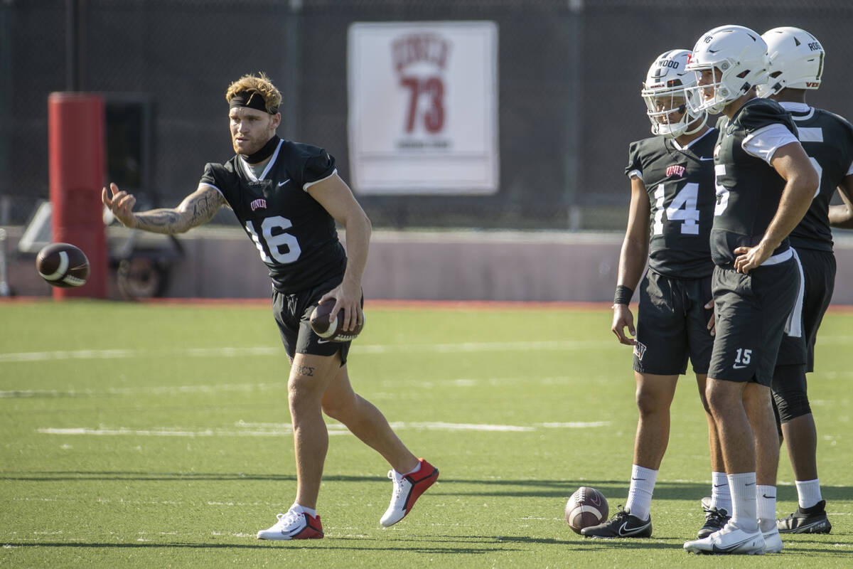 UNLV quarterback Tate Martell (16, left) tosses in a ball to a teammate as other quarterbacks l ...