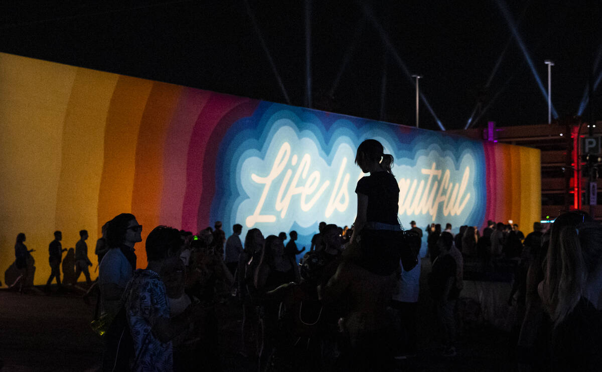 Attendees are silhouetted against a mural during the final day of the Life is Beautiful festiva ...