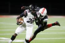 Faith Lutheran High School's Drais Bellamy (20) is tackled by Liberty High School's Landon Bell ...