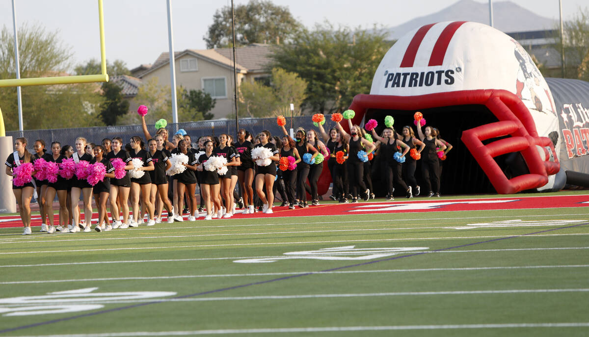 Liberty High School's cheerleaders and dance team members march to the field before a football ...