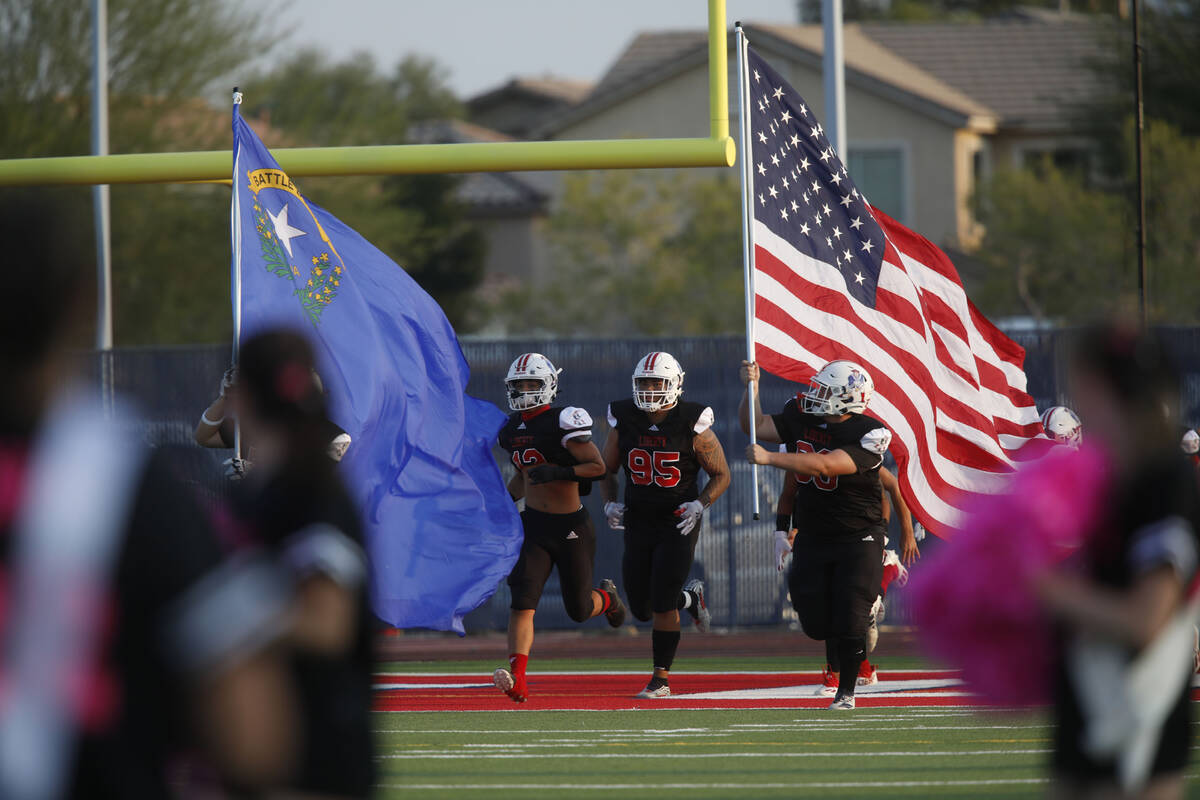 Liberty High School's players run out to the field before the start of before a football game a ...