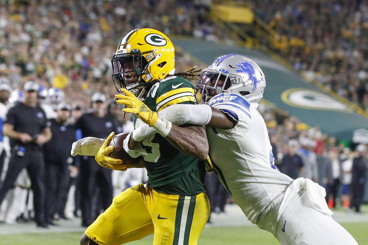 Green Bay Packers running back Aaron Jones, left, scores a touchdown as he is tackled by Detroi ...