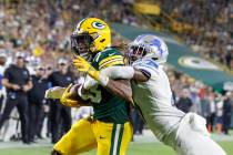 Green Bay Packers running back Aaron Jones, left, scores a touchdown as he is tackled by Detroi ...