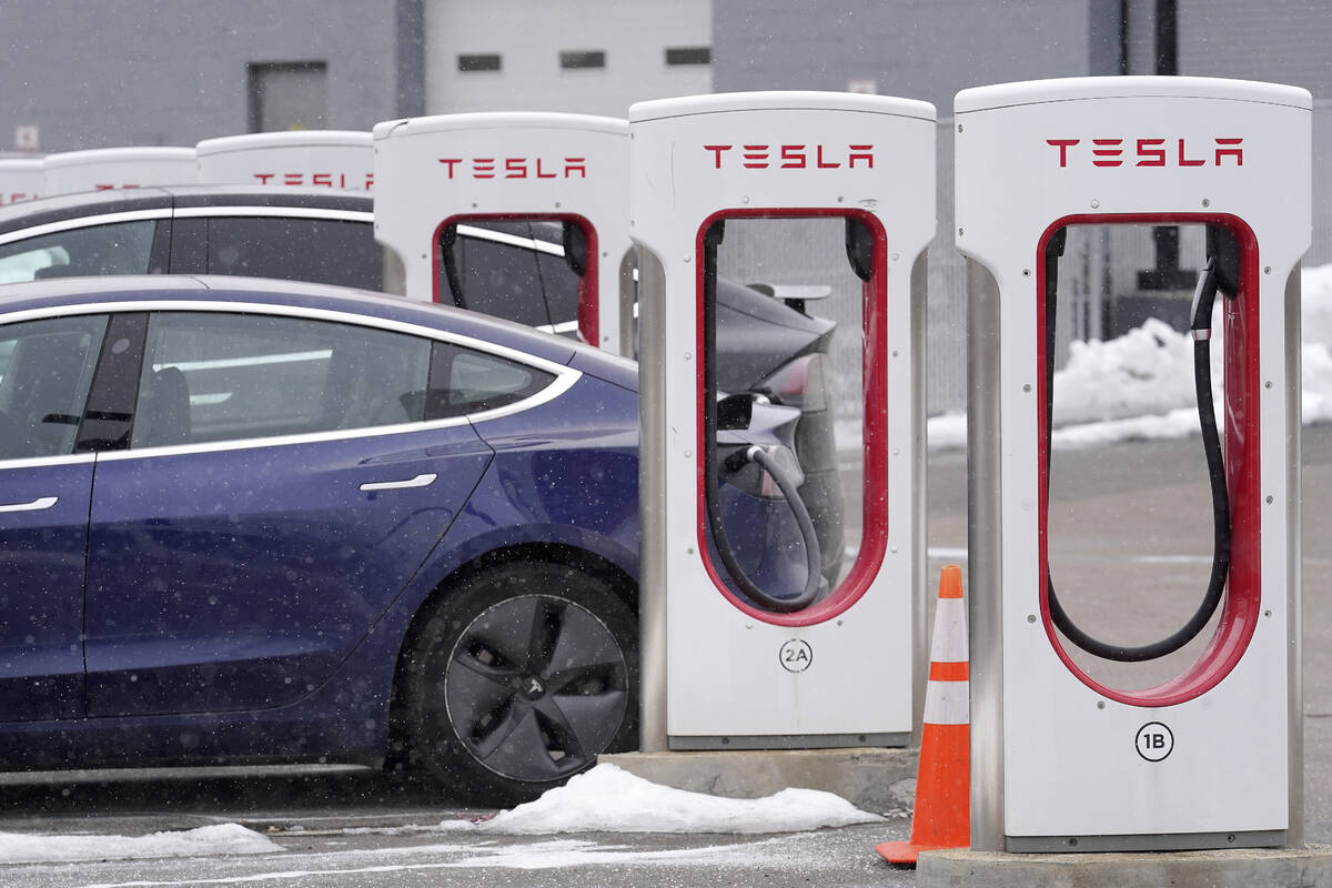 A Tesla electric vehicle, left, sits in a charging station at a dealership, Thursday, Feb. 18, ...