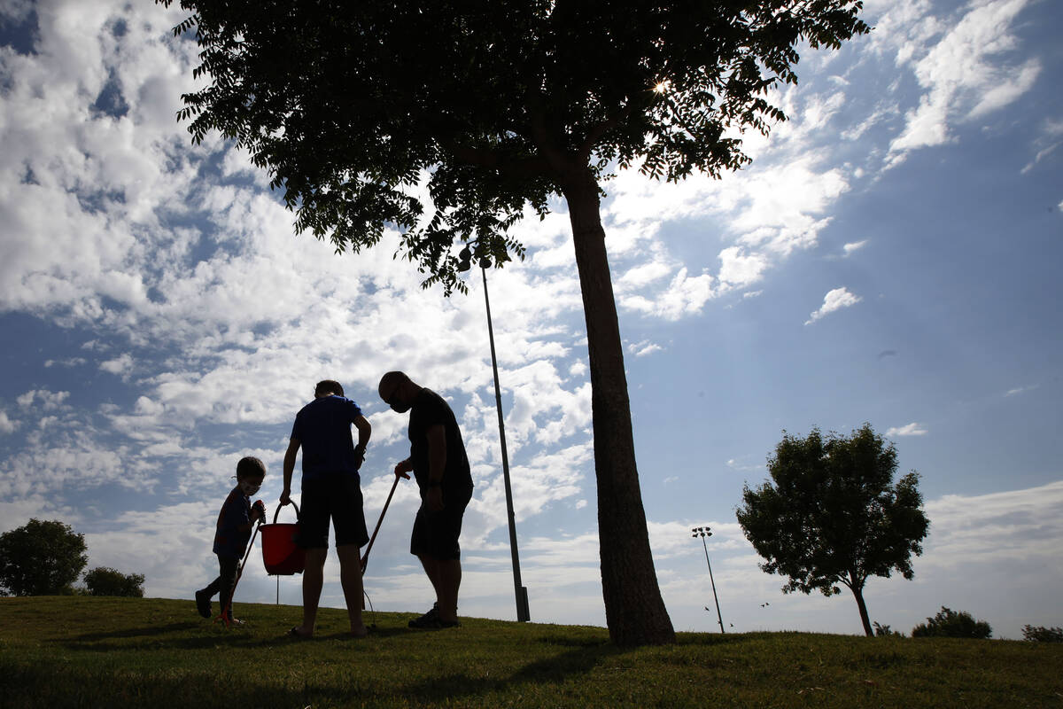 Calvin Muraco of Las Vegas, 4, left, picks up trash with his sister Ainslee, 10, center and his ...