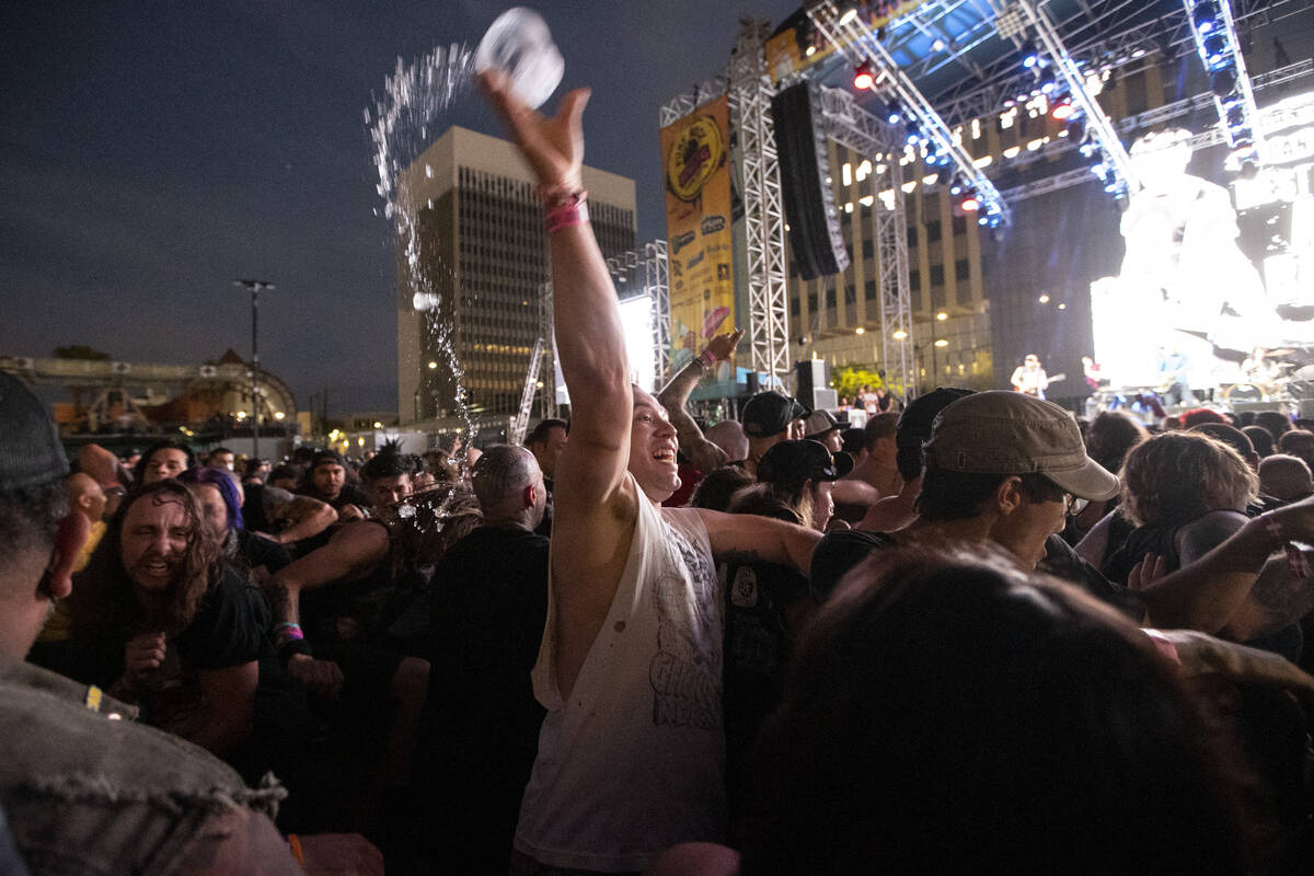 A person throws a drink in the air during a performance by Leftover Crack at the Punk Rock Bowl ...