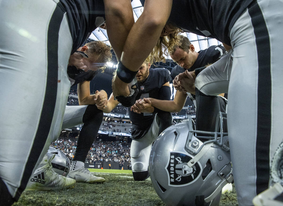 Raiders players pray together on the field after defeating the Miami Dolphins 31-28 in the over ...