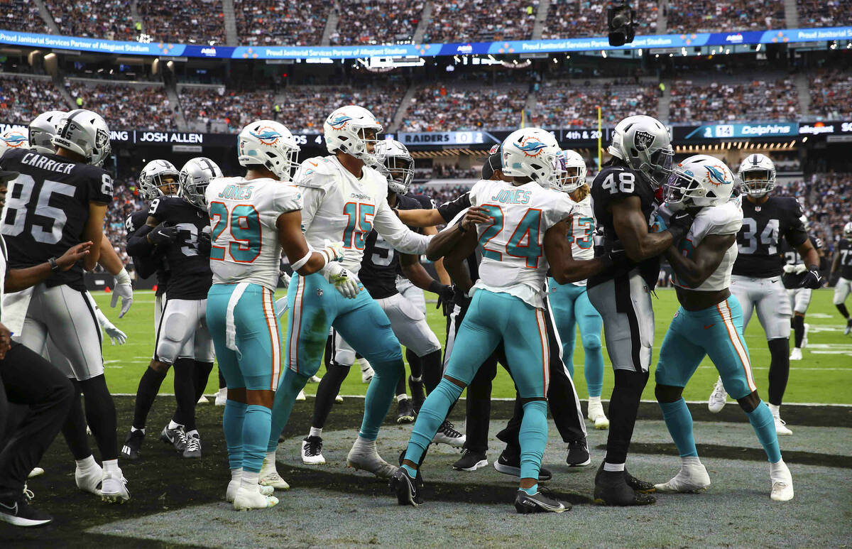 Referees try to break up the Miami Dolphins and Raiders during the first half of NFL game at Al ...