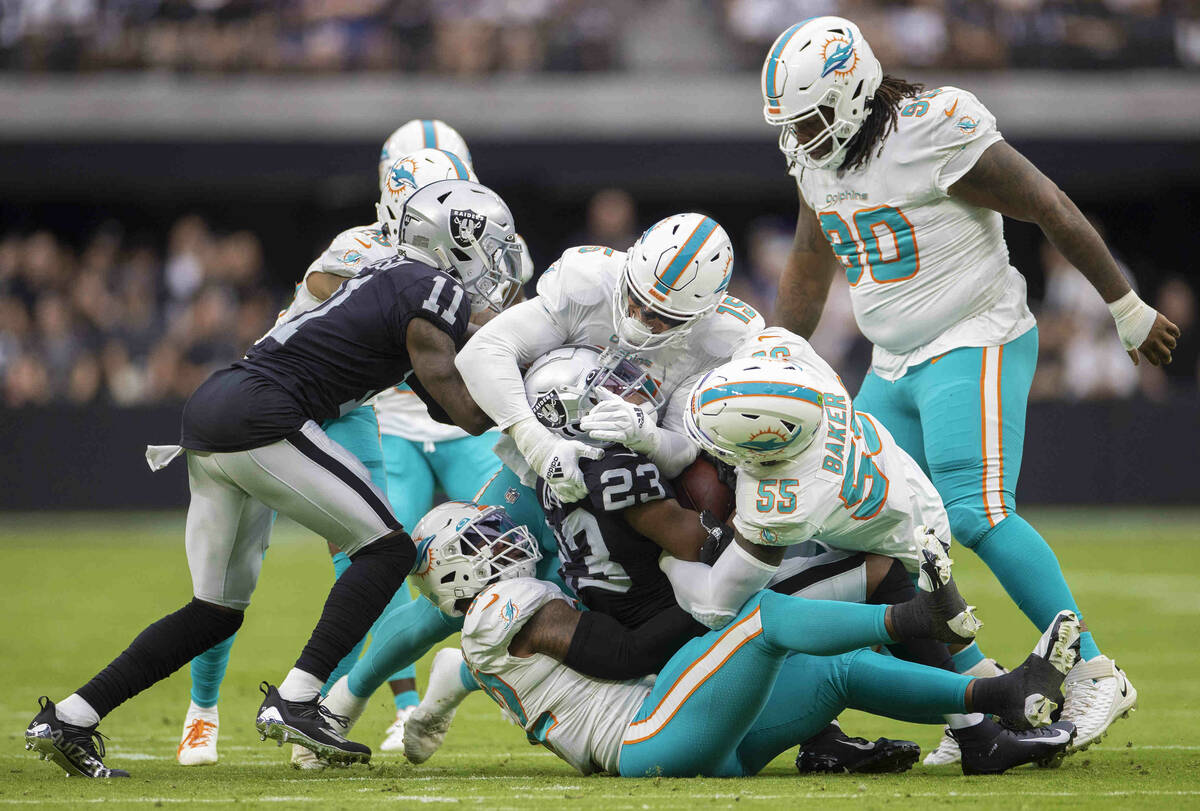 Las Vegas Raiders running back Kenyan Drake (23) is gang tackled by Miami Dolphin defenders in ...