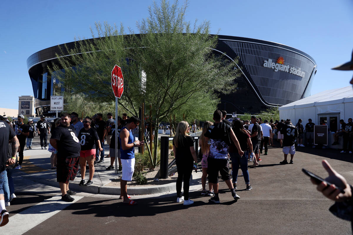 People line up to get the COVID-19 vaccine before the start of an NFL football game between the ...