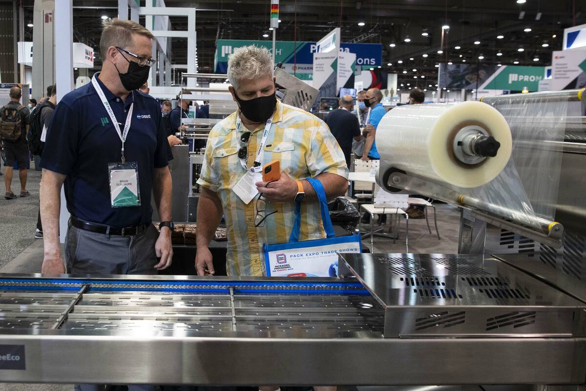 Brian Guillaume, left, of ProMach, talks about ReeEco, an automatic tray sealer, to a potential ...