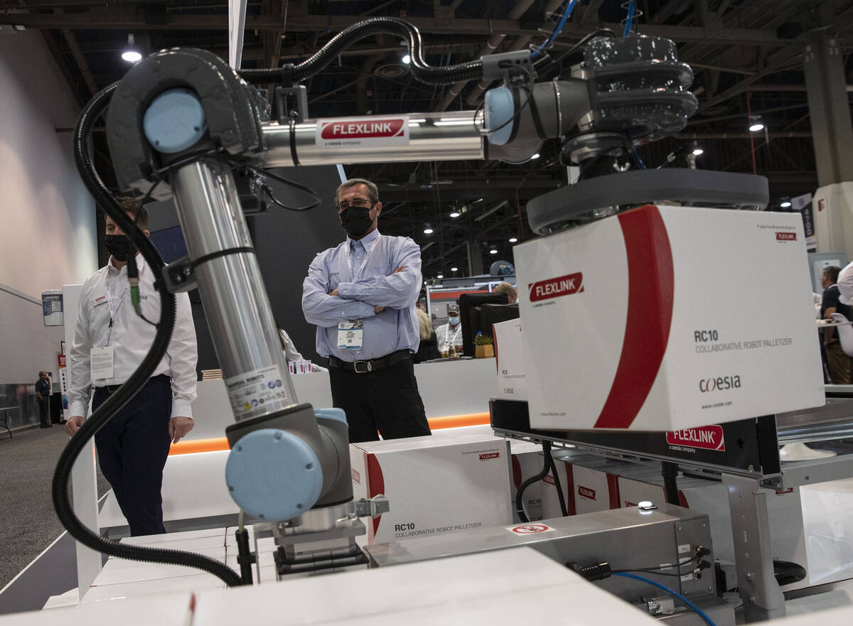 Dave Lynch, right, and David Shaw, both of Flexlink, watch as a box being carried away by RC10, ...