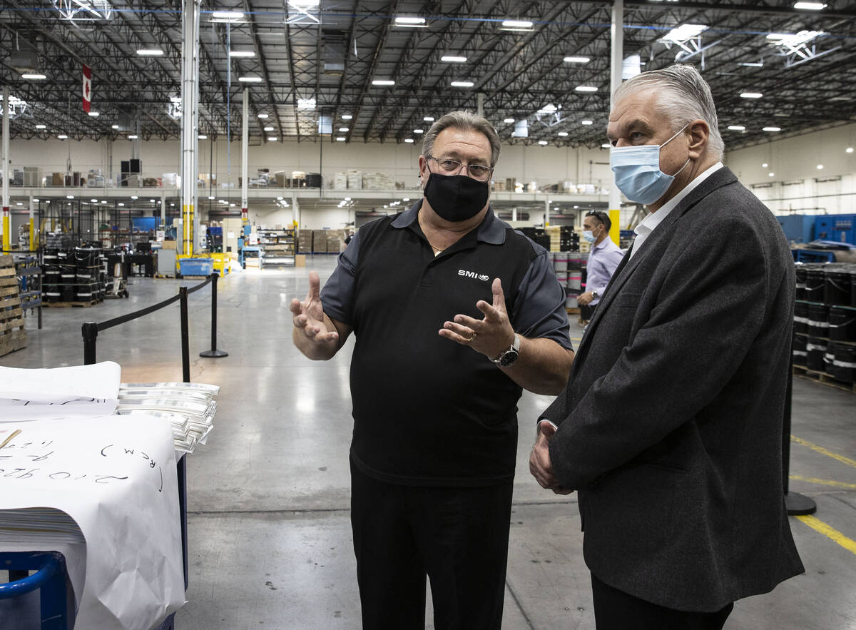 Gov. Steve Sisolak listens to Thomas Power, left, president and CEO of Sunshine Minting Inc., d ...