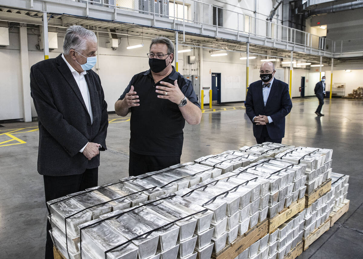 Gov. Steve Sisolak, left, listens to Thomas Power, president and CEO of Sunshine Minting Inc., ...