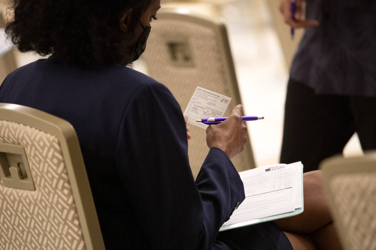 Jessica Dula reviews her vaccination card during a COVID-19 vaccine clinic at Resorts World Las ...