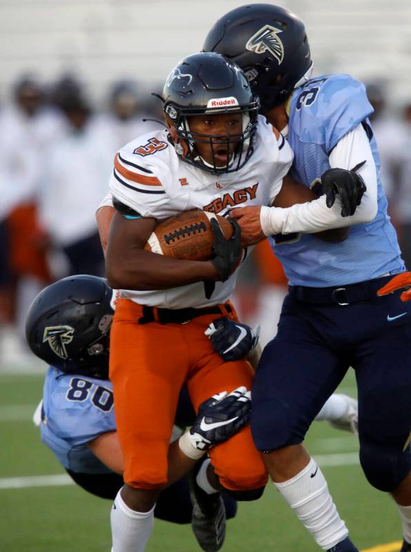 Legacy High School's Khalon White (3) is tackled by Foothill High School's Max Gardner (80) and ...