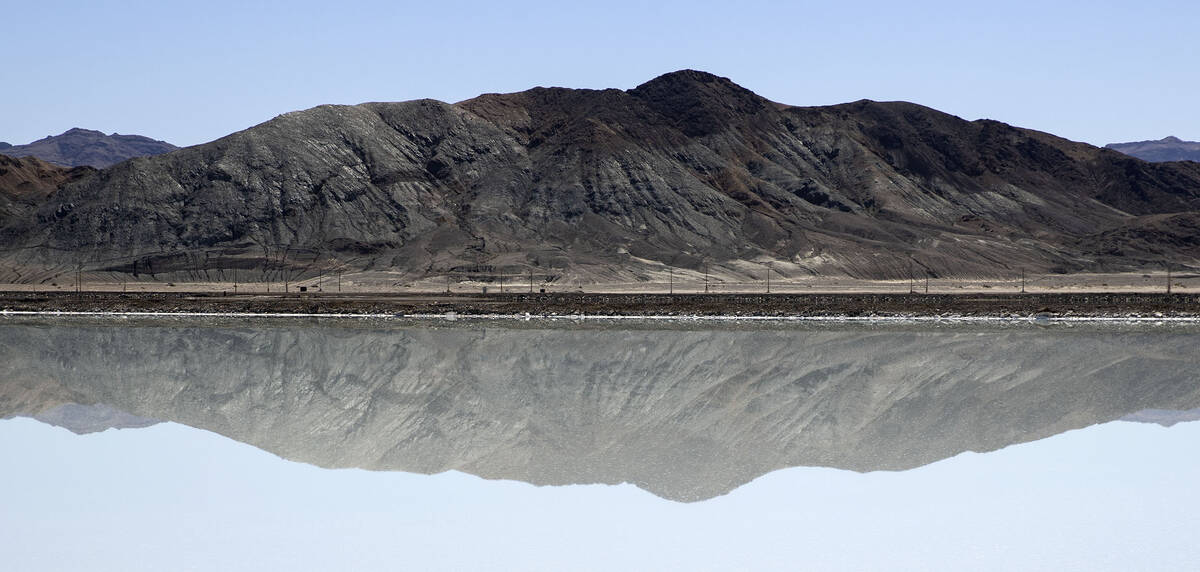 A mountain is reflected in a lithium brine evaporation pond at Albemarle's lithium mine in Silv ...