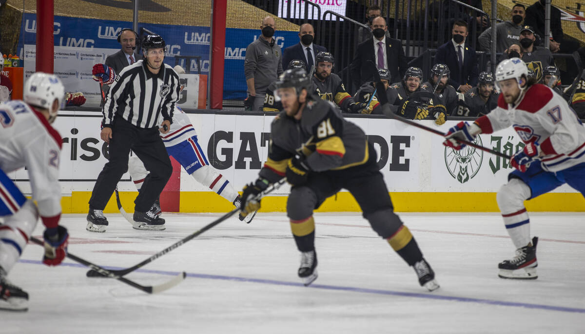 A referee looks on as Golden Knights center Jonathan Marchessault (81) drives the puck past Mon ...