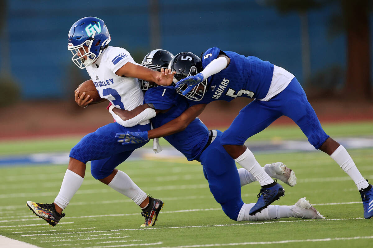 Desert Pines' Tyree Beasley (1) and Jaylen Allen (5) tackle Green Valley's quarterback Josiah ...