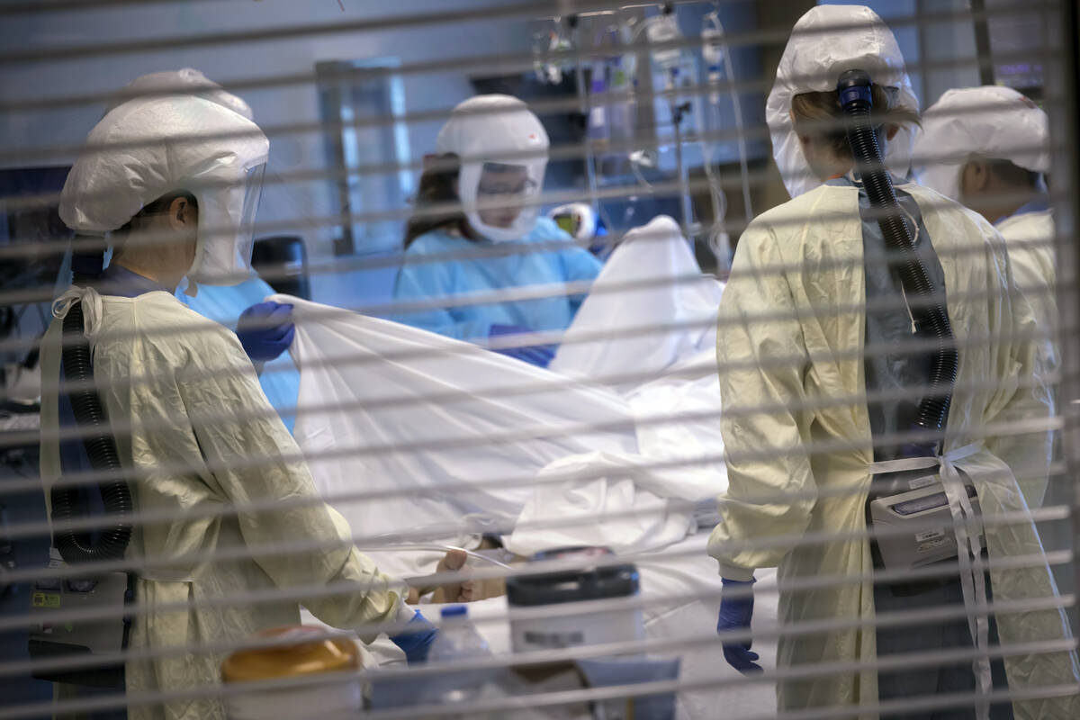 In this image provided by the University of Utah Health, medical professionals look after a COV ...