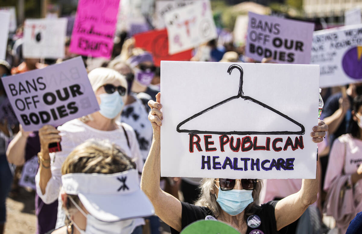 Demonstrators march down South Las Vegas Boulevard past the Lloyd D George Courthouse during a ...