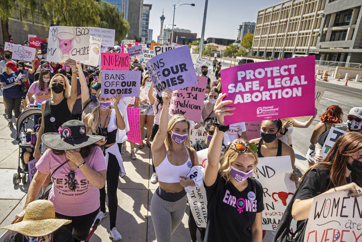 Demonstrators march down South Las Vegas Boulevard past the Lloyd D George Courthouse during a ...