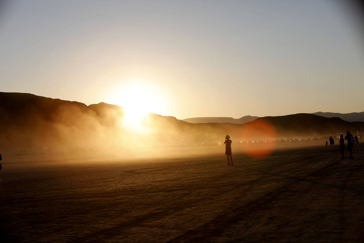 A woman takes photos at sunset during the Rise Festival in the Mojave Desert, Nev, Saturday, Oc ...