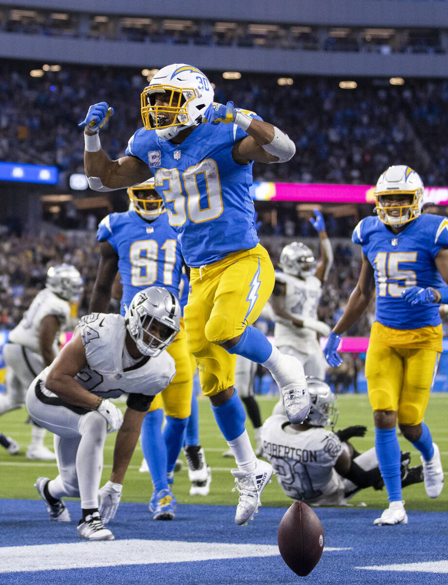 Los Angeles Chargers running back Austin Ekeler (30) leaps into the end zone past Raiders defen ...