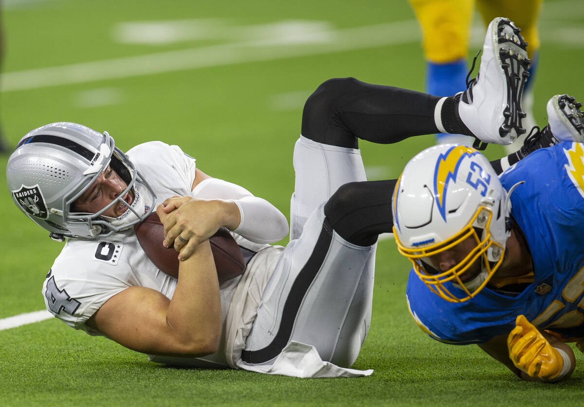 Raiders quarterback Derek Carr (4) holds onto the football after being sacked by Los Angeles Ch ...