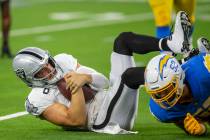 Raiders quarterback Derek Carr (4) holds onto the football after being sacked by Los Angeles Ch ...