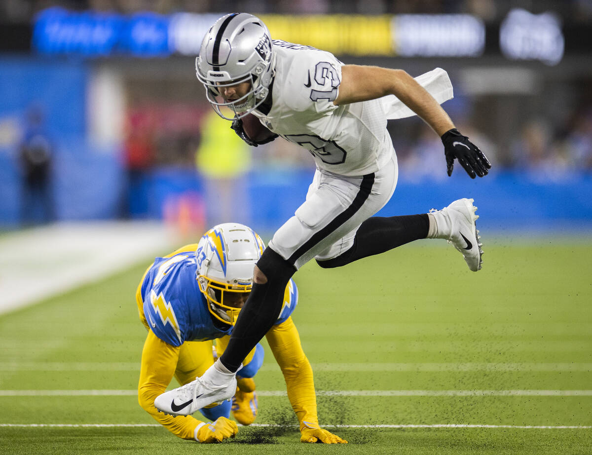 Raiders wide receiver Hunter Renfrow (13) fights for extra yardage past Los Angeles Chargers co ...